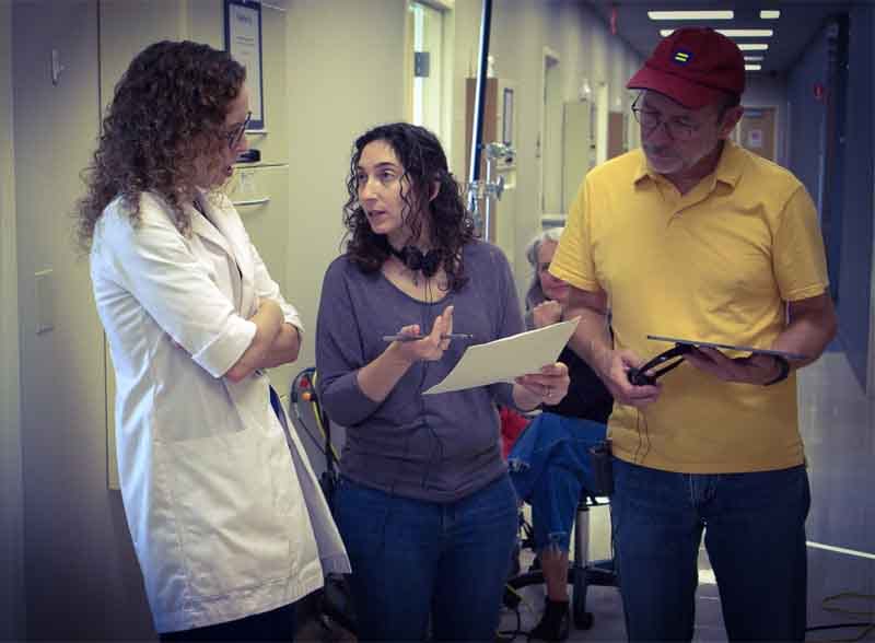 2 women and a man in a hospital. One of the women is explaining to the doctor while the man looks at the paper in the woman's hand.